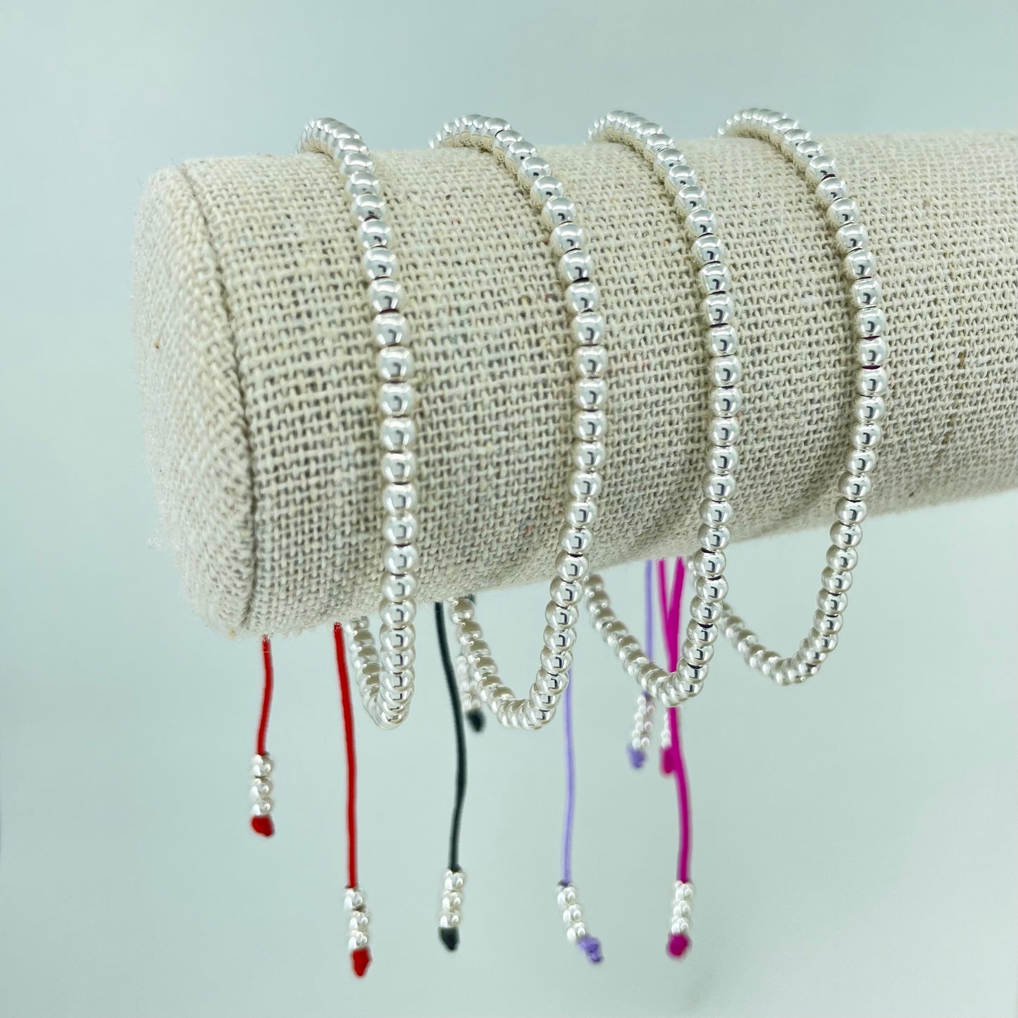 Pulsera de Bolitas de Plata sobre un Hilo de Color.